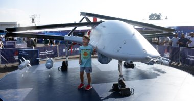 A boy poses for a photo beside Bayraktar TB3 unmanned combat aerial vehicle at the aerospace and technology festival Teknofest, in Izmir, western Türkiye, Sept. 27, 2023. (DHA Photo)