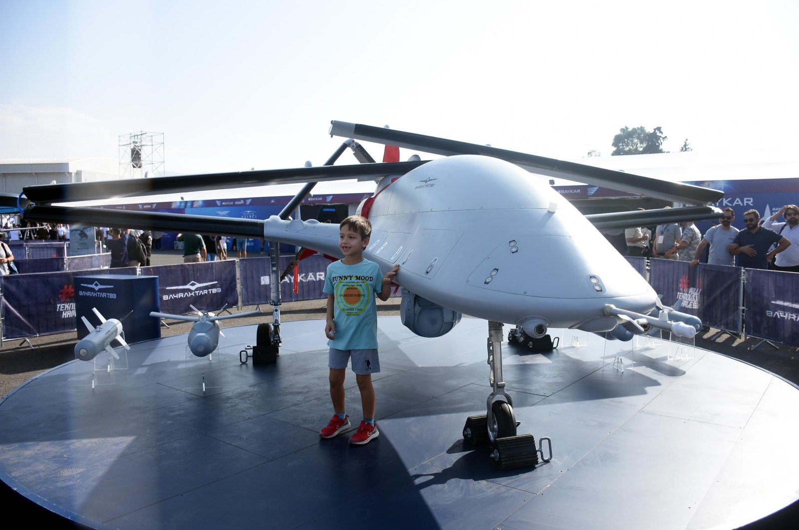 A boy poses for a photo beside Bayraktar TB3 unmanned combat aerial vehicle at the aerospace and technology festival Teknofest, in Izmir, western Türkiye, Sept. 27, 2023. (DHA Photo)