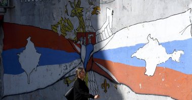 A woman walks in front of a mural in the ethnically divided city of Mitrovica, Kosovo, Sept. 28, 2023. (AFP Photo)