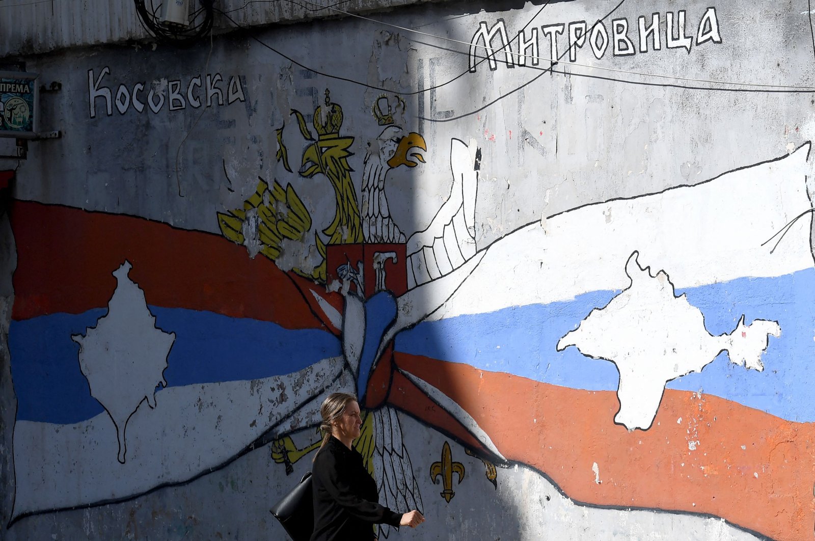 A woman walks in front of a mural in the ethnically divided city of Mitrovica, Kosovo, Sept. 28, 2023. (AFP Photo)