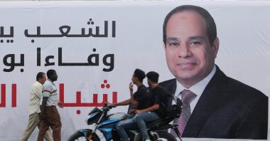 People walk past a banner depicting Egypt's President Abdel Fattah el-Sissi, as people prepare for a rally to support him in the upcoming presidential election in December, in Cairo, Egypt, Oct. 2, 2023. (Reuters Photo)