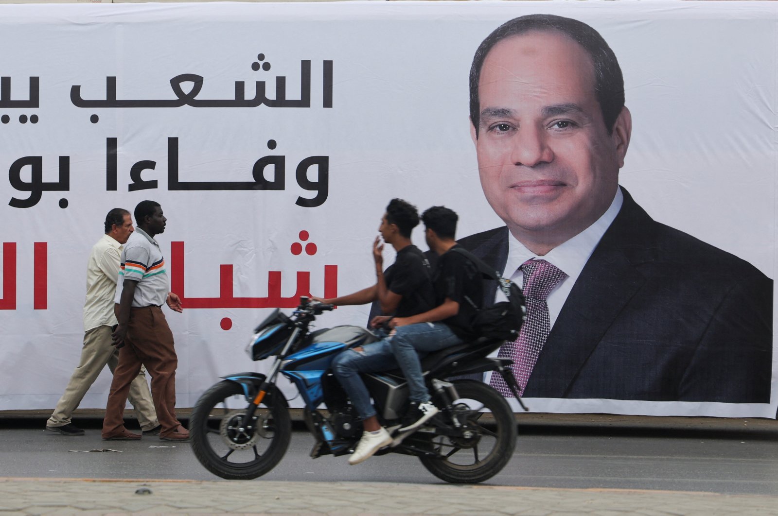 People walk past a banner depicting Egypt&#039;s President Abdel Fattah el-Sissi, as people prepare for a rally to support him in the upcoming presidential election in December, in Cairo, Egypt, Oct. 2, 2023. (Reuters Photo)