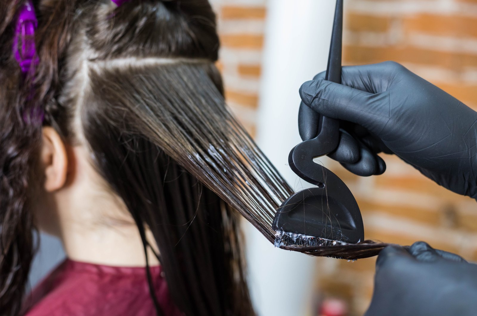 The process of applying liquid keratin using a special hairdressing brush. (Shutterstock Photo)