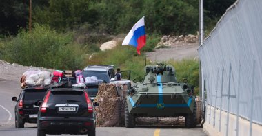 Cars pass next to a Russian peacekeeper vehicle, as they leave Karabakh, in Lachin on Sept. 26, 2023. (AFP File Photo)