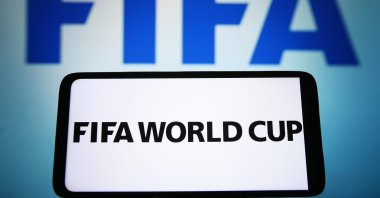 FIFA World Cup words are seen displayed on a smartphone and FIFA logo on the background, March 17, 2023. (Getty Images File Photo)