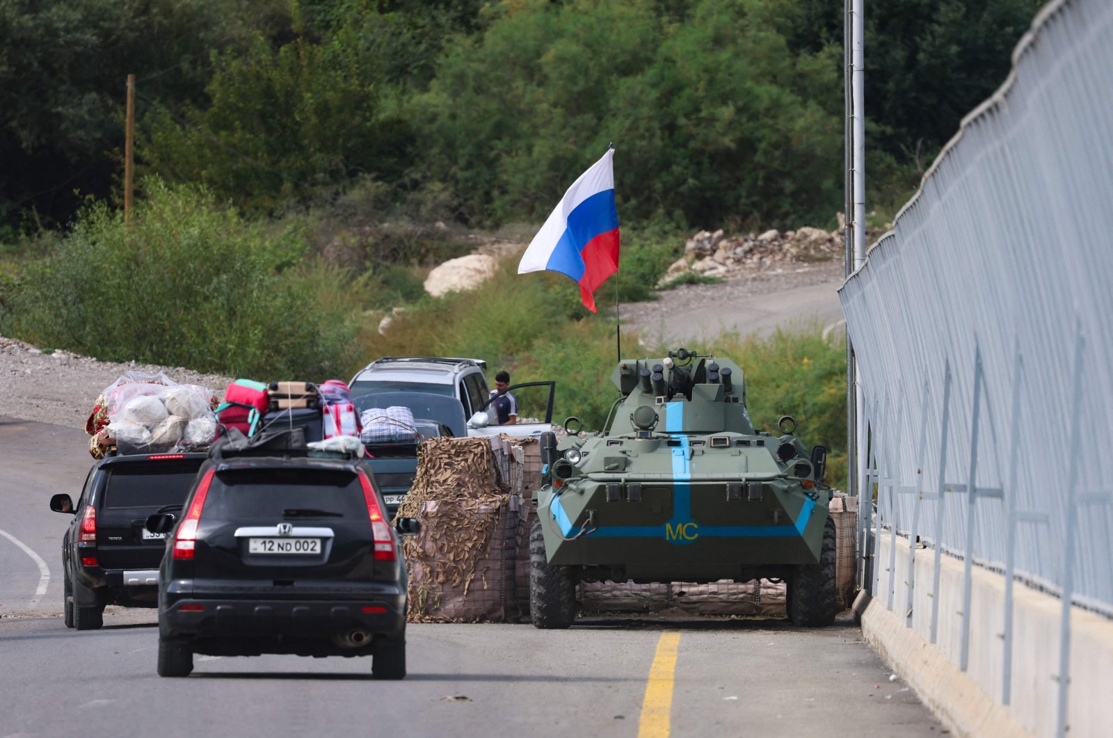 Cars pass next to a Russian peacekeeper vehicle, as they leave Karabakh, in Lachin on Sept. 26, 2023. (AFP File Photo)