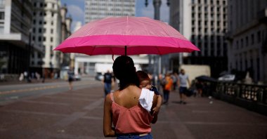 A woman holds her son as they shelter under an umbrella from the sun, Sao Paulo, Brazil, Sept. 22, 2023. (Reuters Photo)