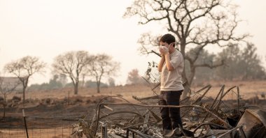 A child adjusts his face mask while searching through the burned remains of their home in Paradise, California, U.S., Nov. 18, 2018. (AFP Photo)
