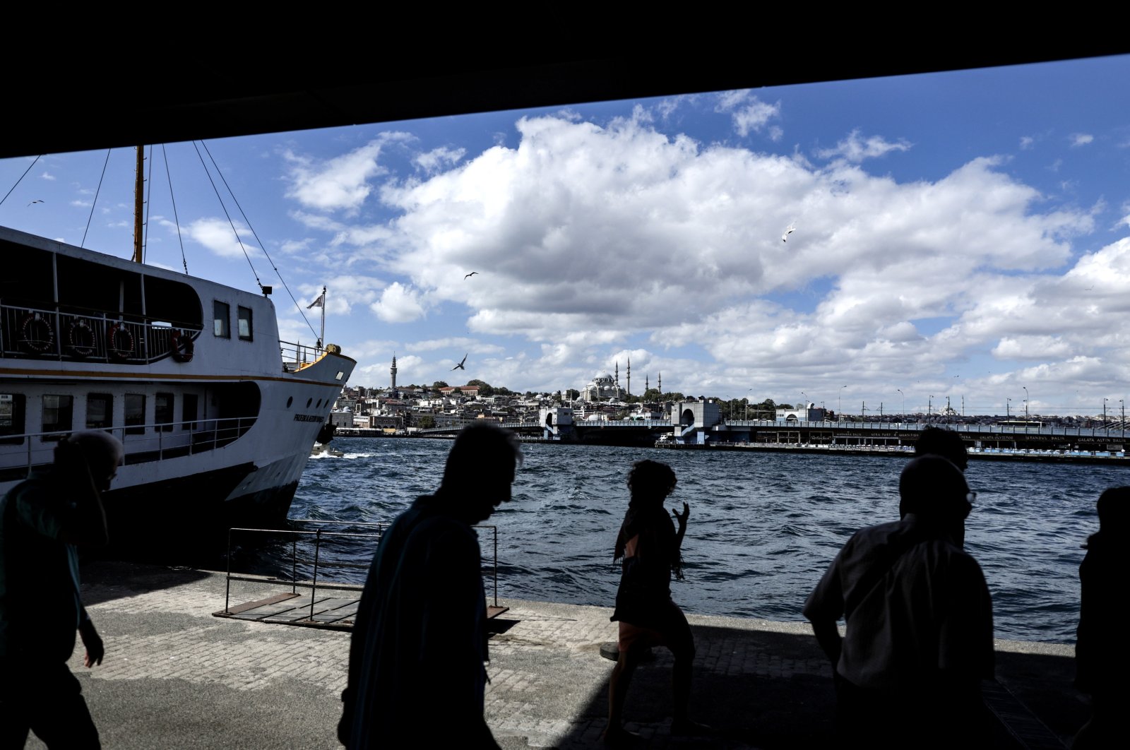 People are silhouetted as they walk near the Bosporus backdropped by the Süleymaniye Mosque and the Galata Bridge, Istanbul, Türkiye, Sept. 11, 2023. (EPA Photo)