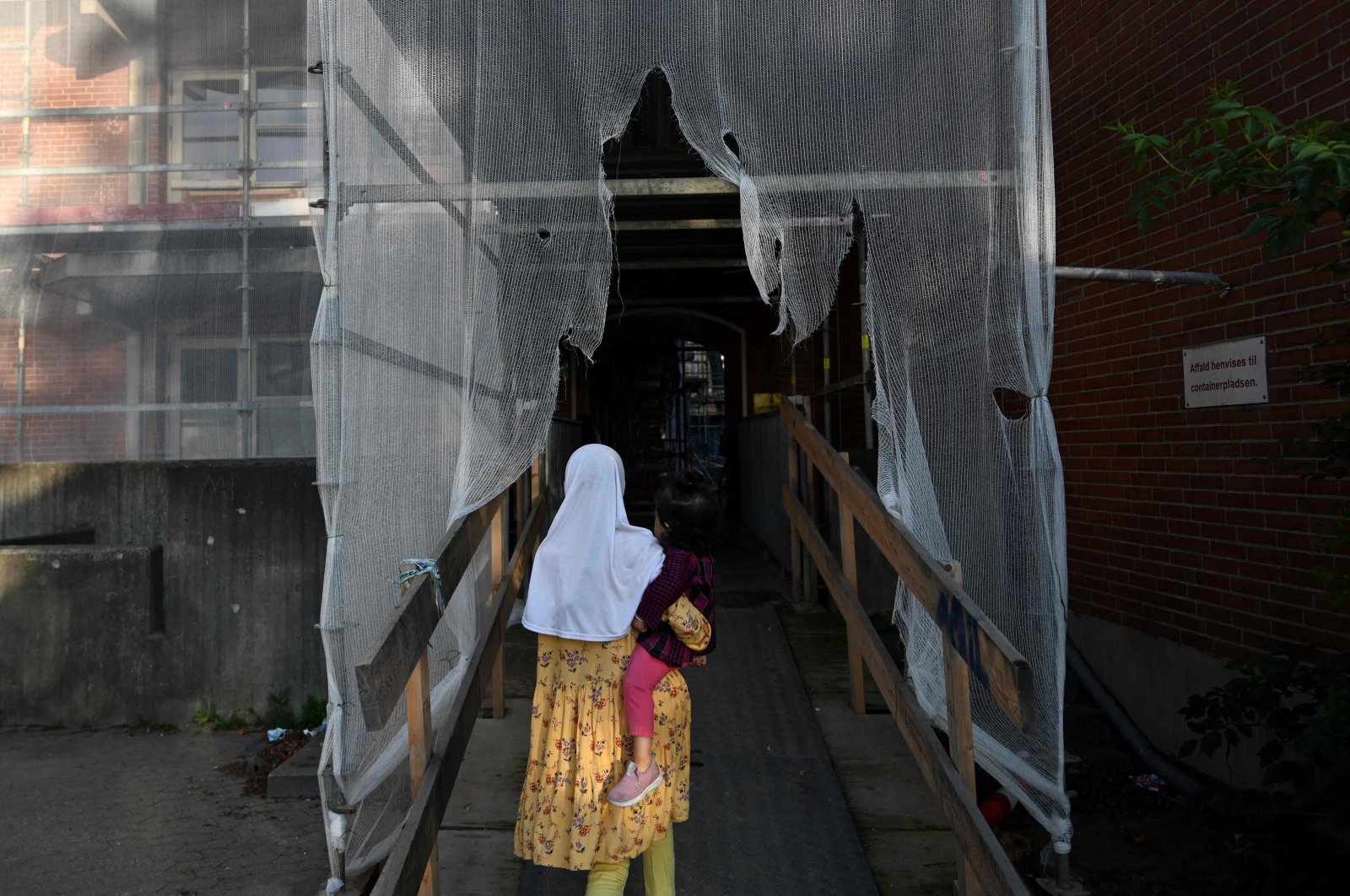 A girl with a child enters a residential building of Mjolnerparken housing estate in Copenhagen, Denmark, Aug. 28, 2023. (AFP Photo)