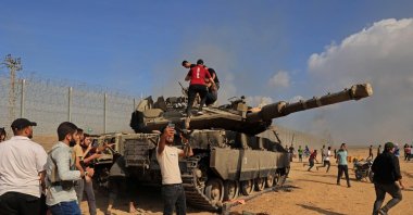 Palestinians take control of an Israeli tank after crossing the border fence with Israel from Khan Yunis in the southern Gaza Strip on Oct. 7, 2023. (AFP Photo)