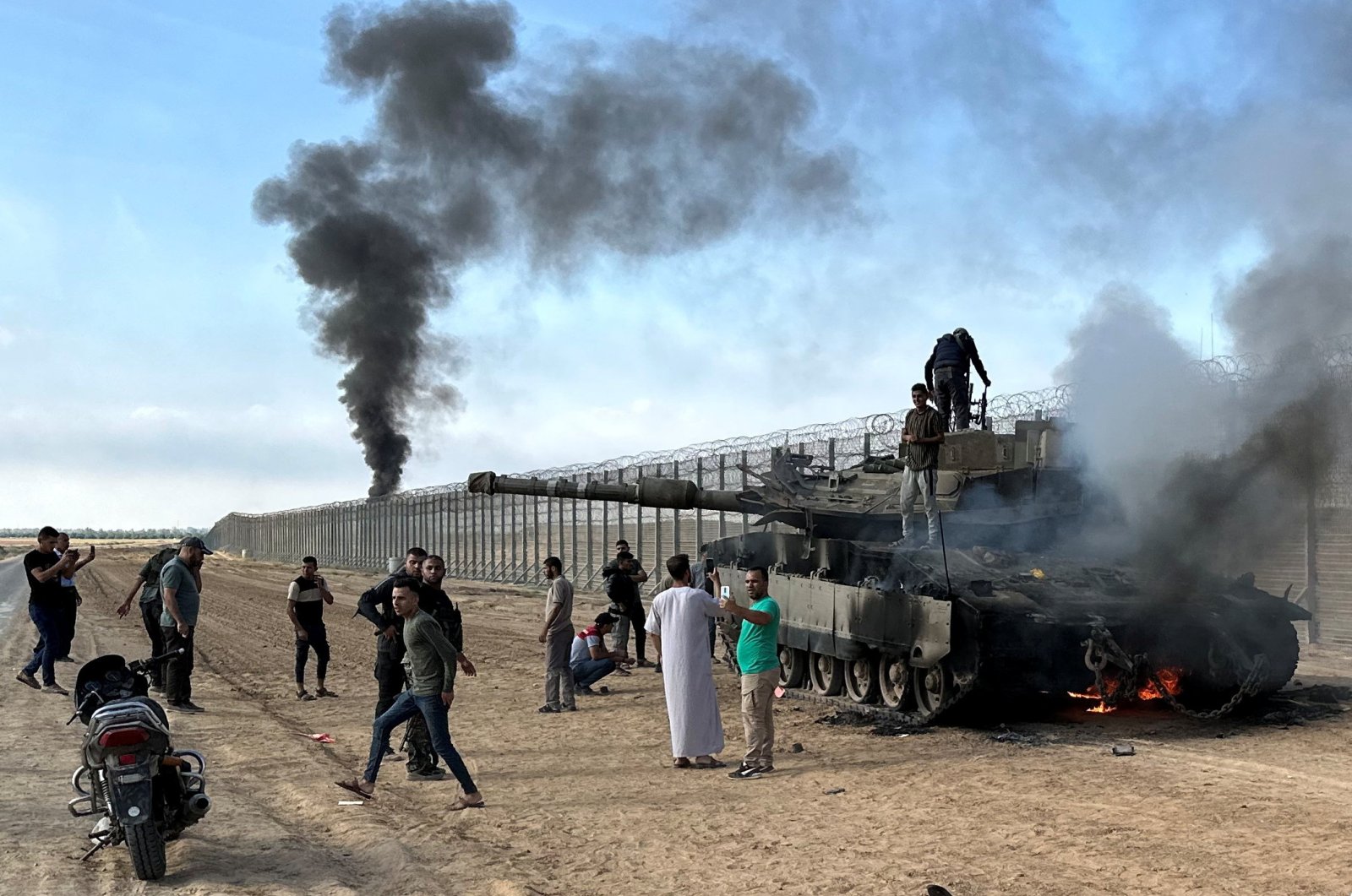Palestinians react as an Israeli military vehicle burns at the Israeli side of the Israel-Gaza border, Oct. 7, 2023. (Reuters Photo)