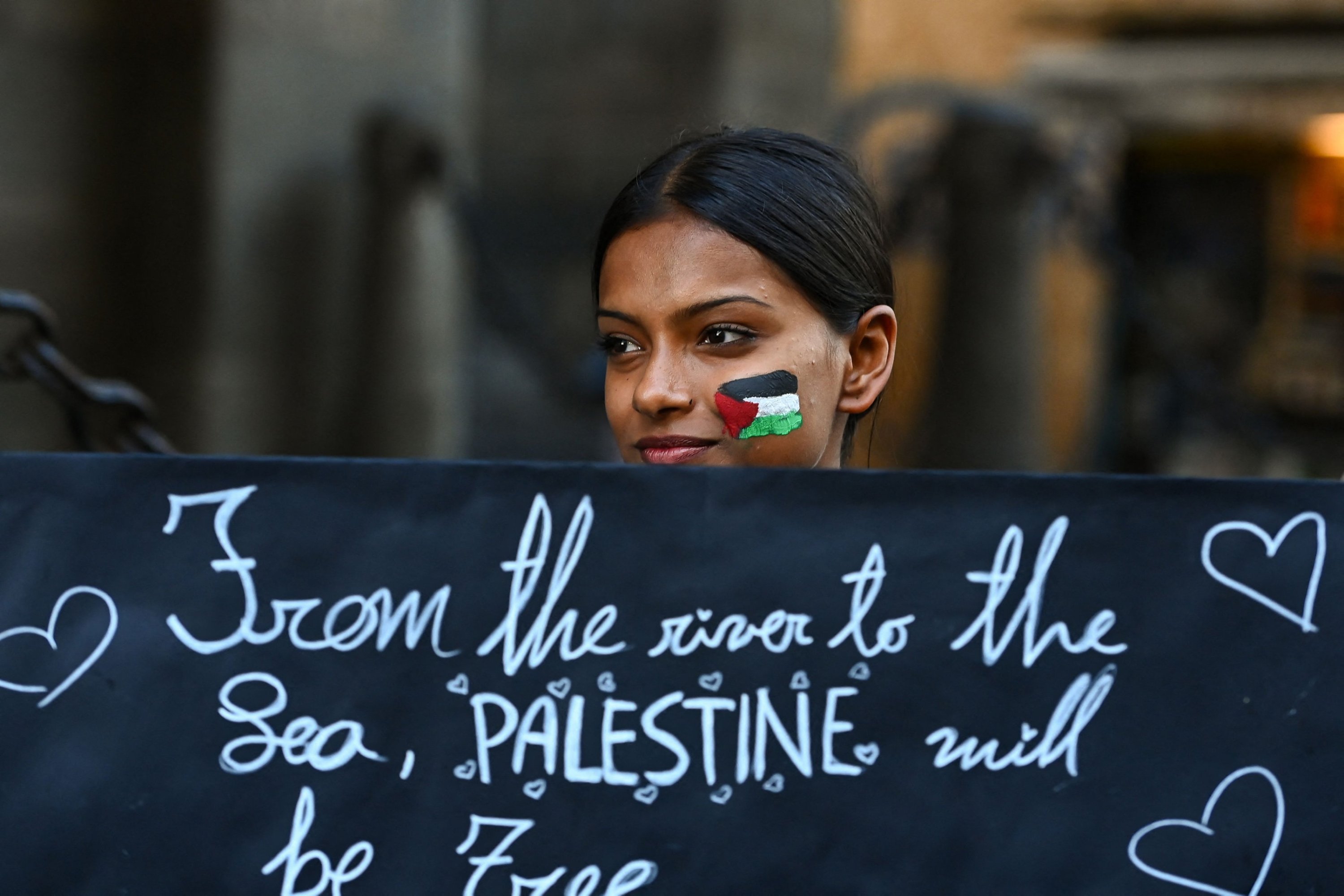 A demonstrator holds a placard reading 'From the river to the Lea, Palestine will be free' during a rally in support of Palestinians in central Milan, Italy on Oct. 10, 2023. (AFP Photo)