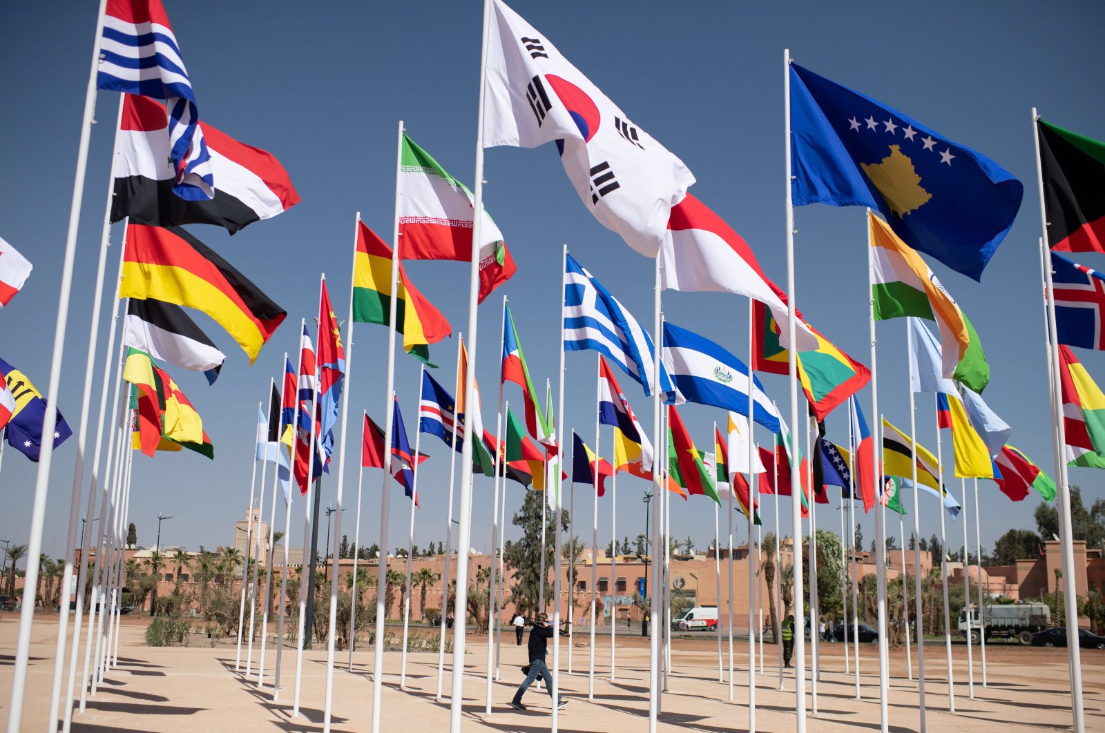 A man walks past flags at the entrance to the 2023 annual meetings of the International Monetary Fund and the World Bank, Marrakesh, Morocco, Oct. 8, 2023. (EPA Photo)