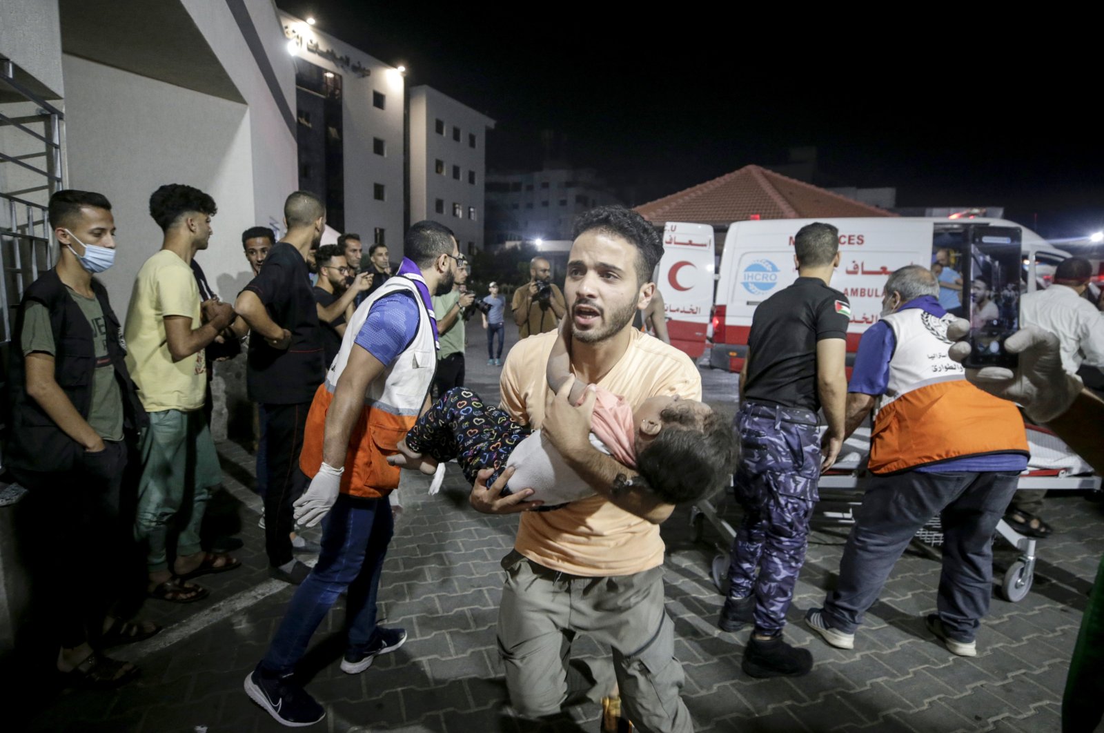 A Palestinian man carries a wounded child at Al-Shifa hospital in Gaza City, Oct. 9,  2023. (EPA Photo)