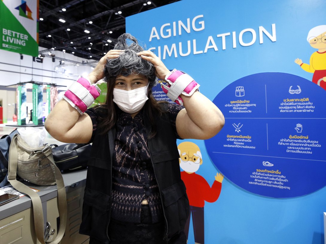 A visitor adjusts a white hair wig to experience aging during an aging simulation at the Sustainability Expo 2023 in Bangkok, Thailand, Oct. 2, 2023. (EPA Photo)