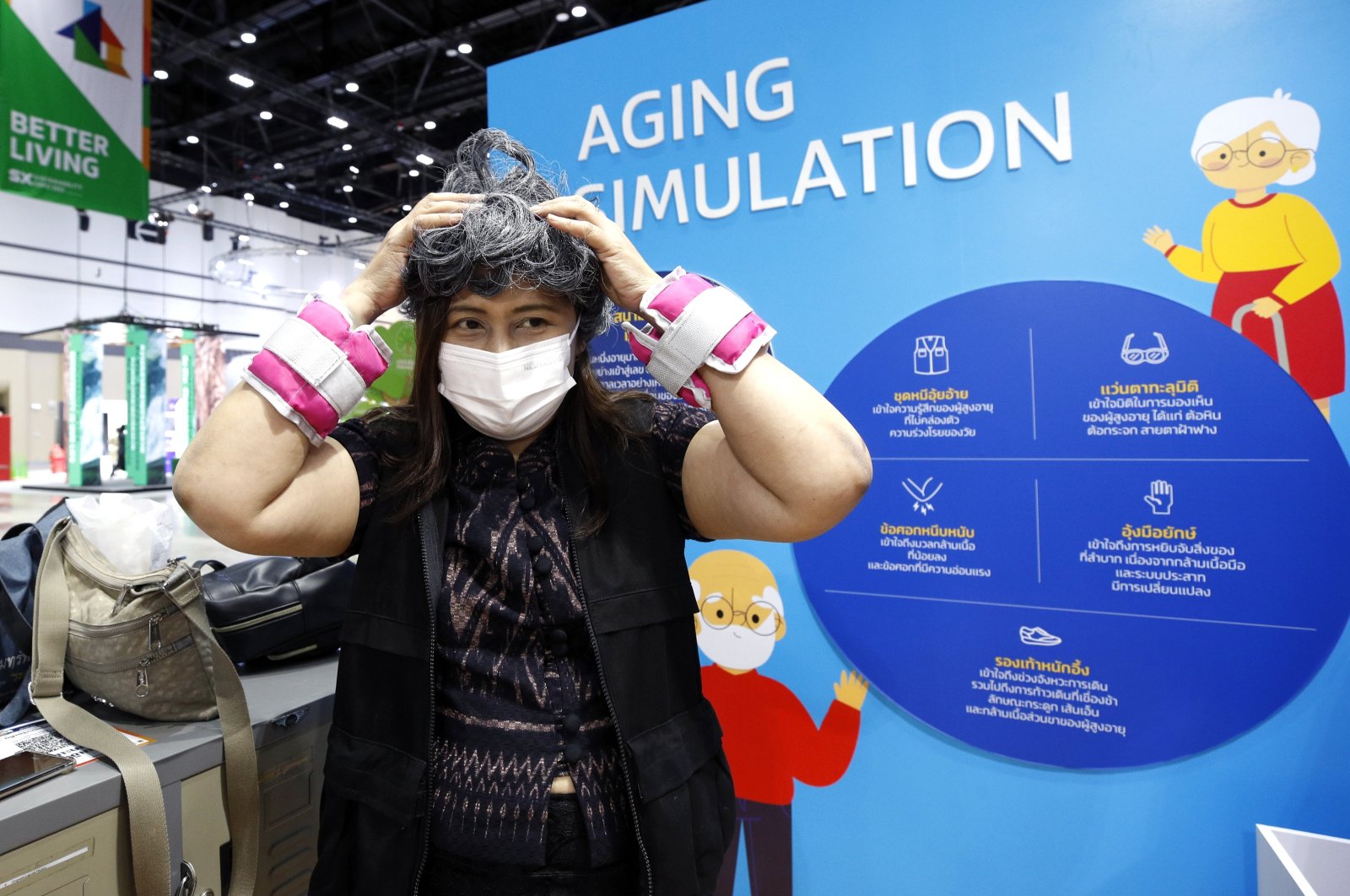 A visitor adjusts a white hair wig to experience aging during an aging simulation at the Sustainability Expo 2023 in Bangkok, Thailand, Oct. 2, 2023. (EPA Photo)