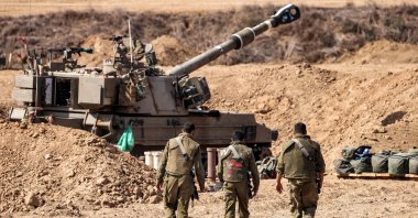 Israeli army soldiers walk near a self-propelled howitzer stationed near the border with Gaza, Oct. 12, 2023. (AFP Photo)