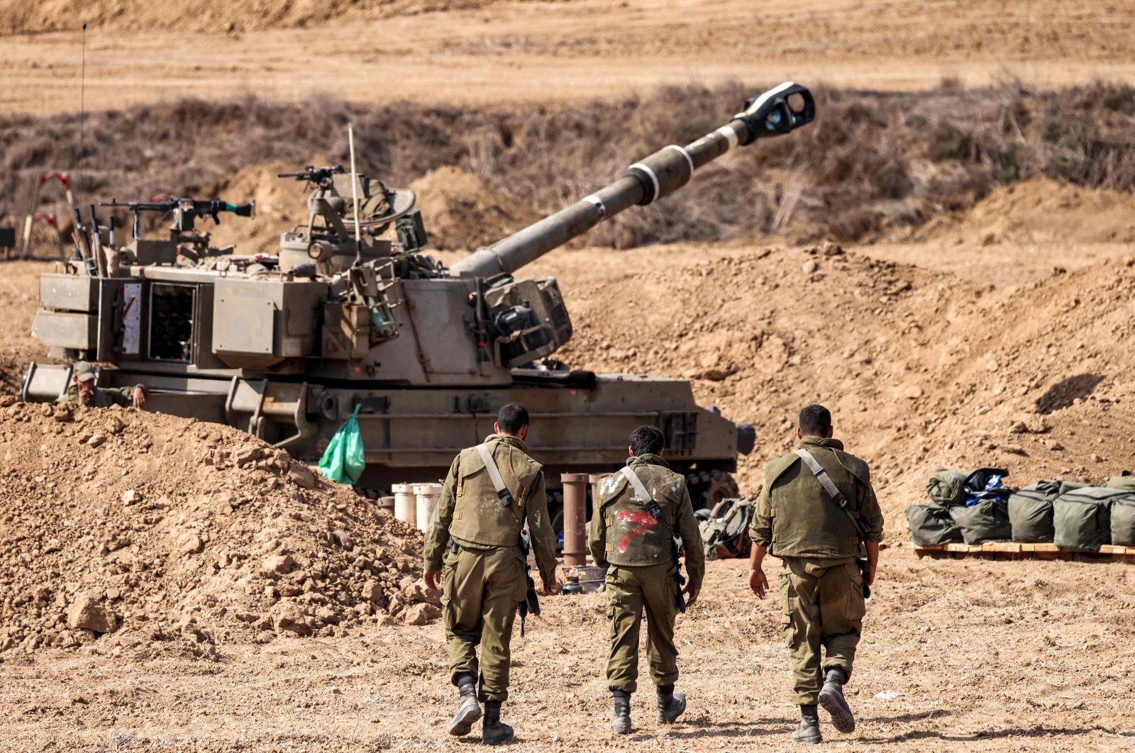 Israeli army soldiers walk near a self-propelled howitzer stationed near the border with Gaza, Oct. 12, 2023. (AFP Photo)