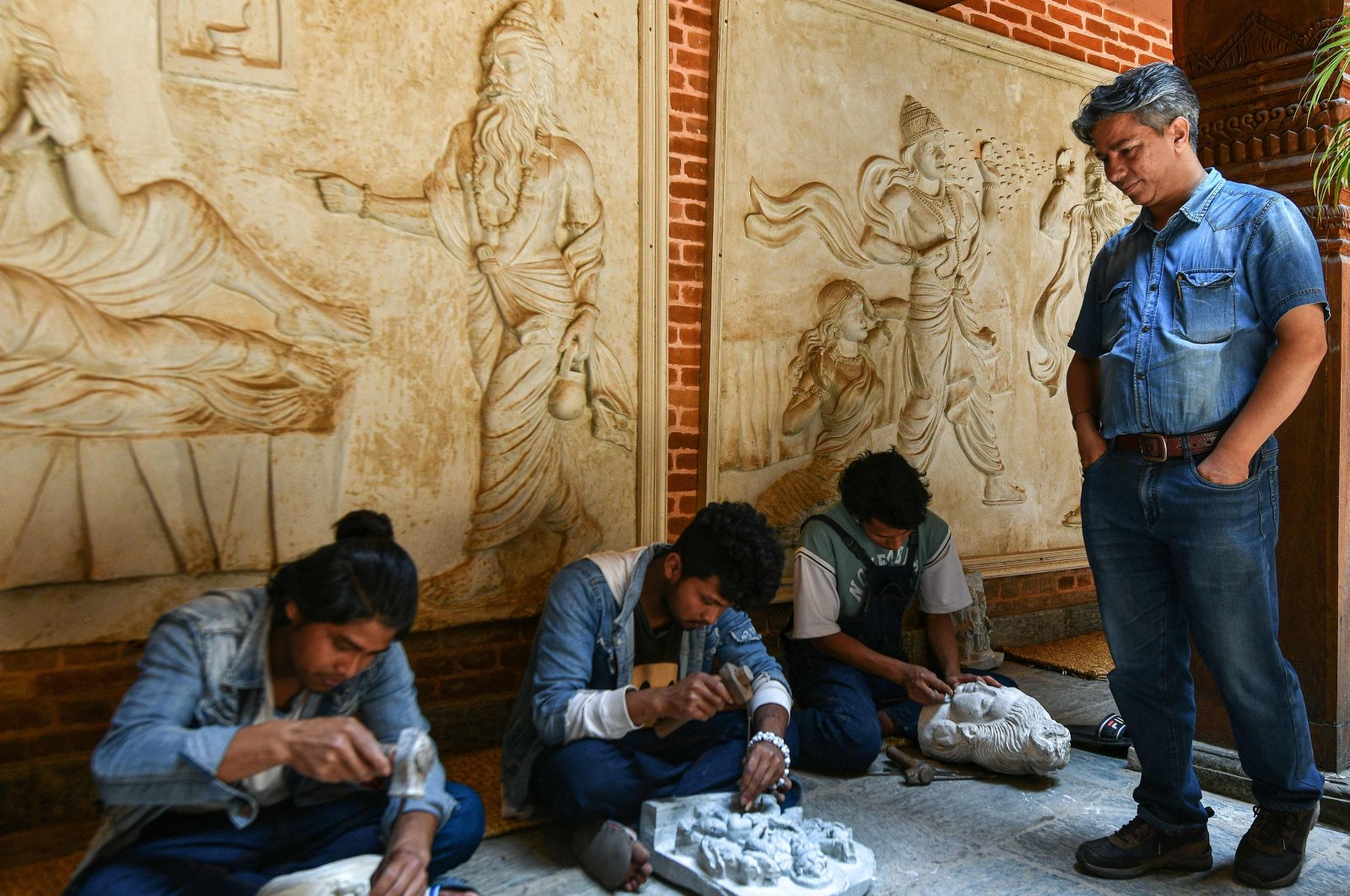 Heritage conservationist and Nepal Vocational Academy founder Rabindra Puri (R) watches artisans sculpt stone structures at the academy in Bhaktapur on the outskirts of Kathmandu, Nepal, July 14, 2023. (AFP Photo)