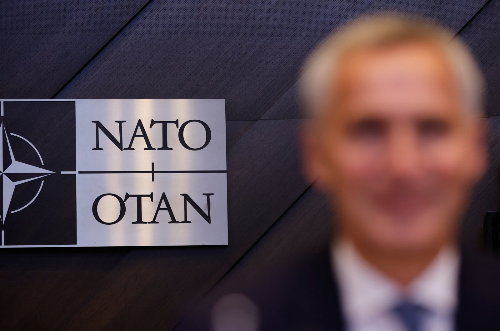 A NATO sign is pictured with NATO Secretary-General Jens Stoltenberg in the foreground, in Brussels, Belgium, Oct. 12, 2023. (Reuters Photo)