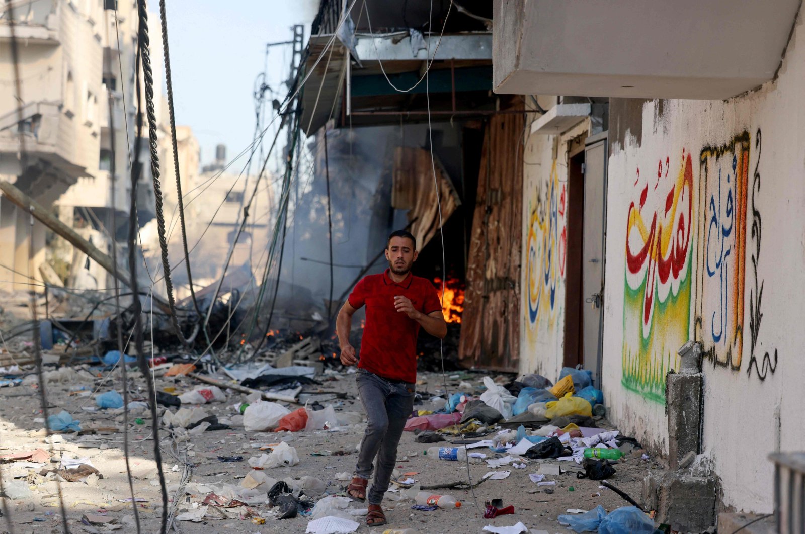 A Palestinian man runs amid the rubble of a building hit in an Israeli air strike, Gaza Strip, Oct. 13, 2023. (AFP Photo)