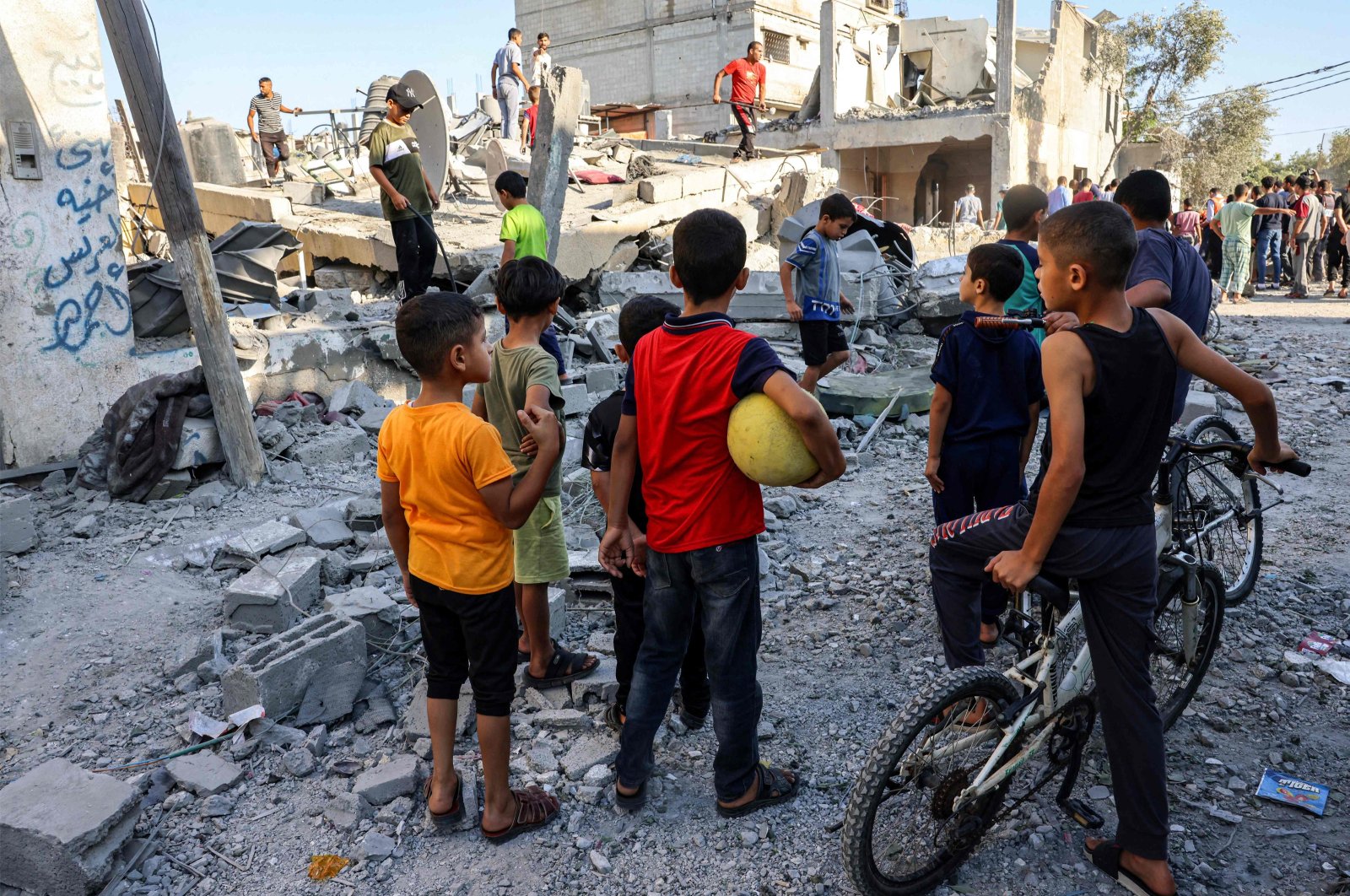 Children watch as civil defense responders search for victims in the rubble of a building after an Israeli air strike in Rafah in the southern Gaza Strip on Oct. 13, 2023. (AFP Photo)