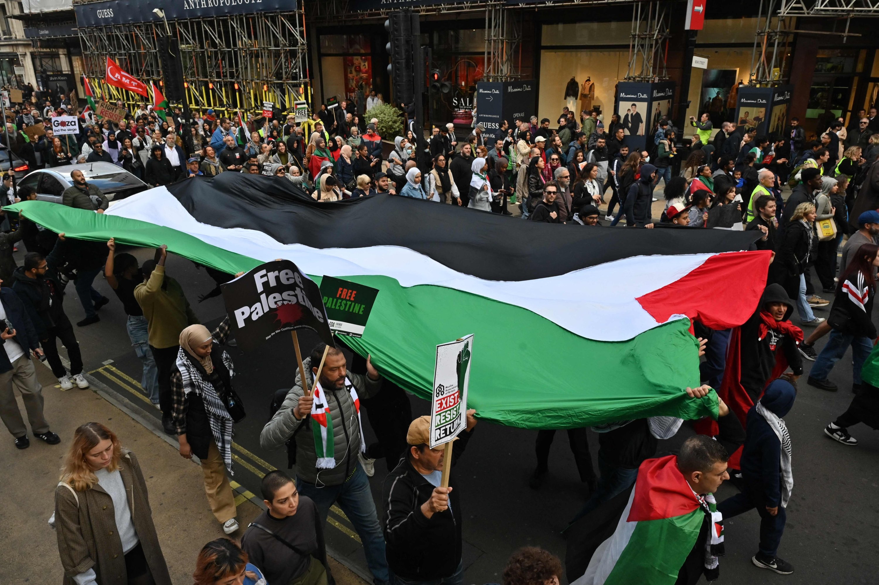 People walk down Regent Street with a large Palestinian flag as they take part in a 