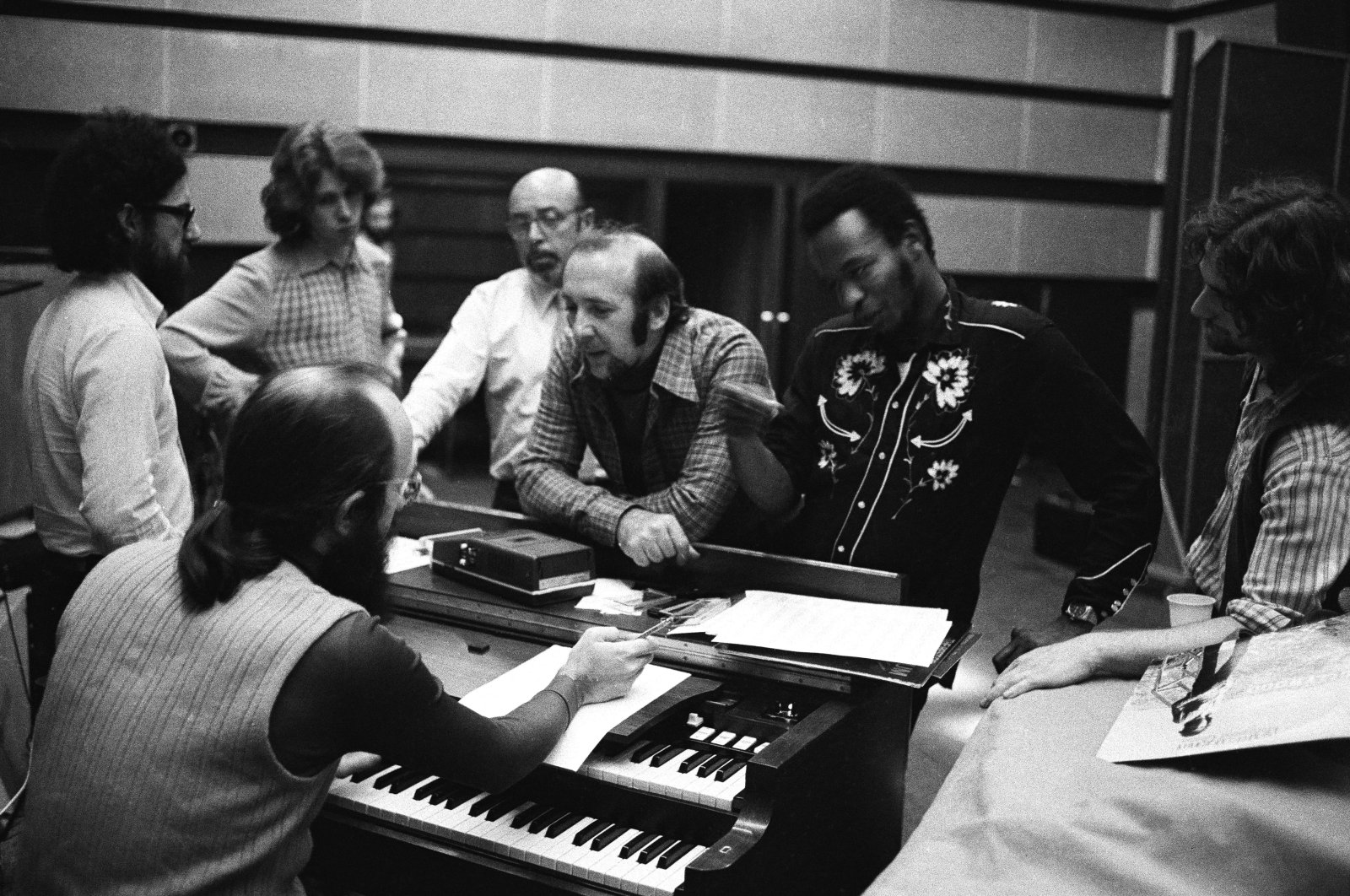 American jazz musician Herbie Mann (1930-2003) leans on a piano (C) at a recording studio with Mick Taylor, Ahmet Ertegün and Albert Lee, among others, 1973. (Getty Images Photo)