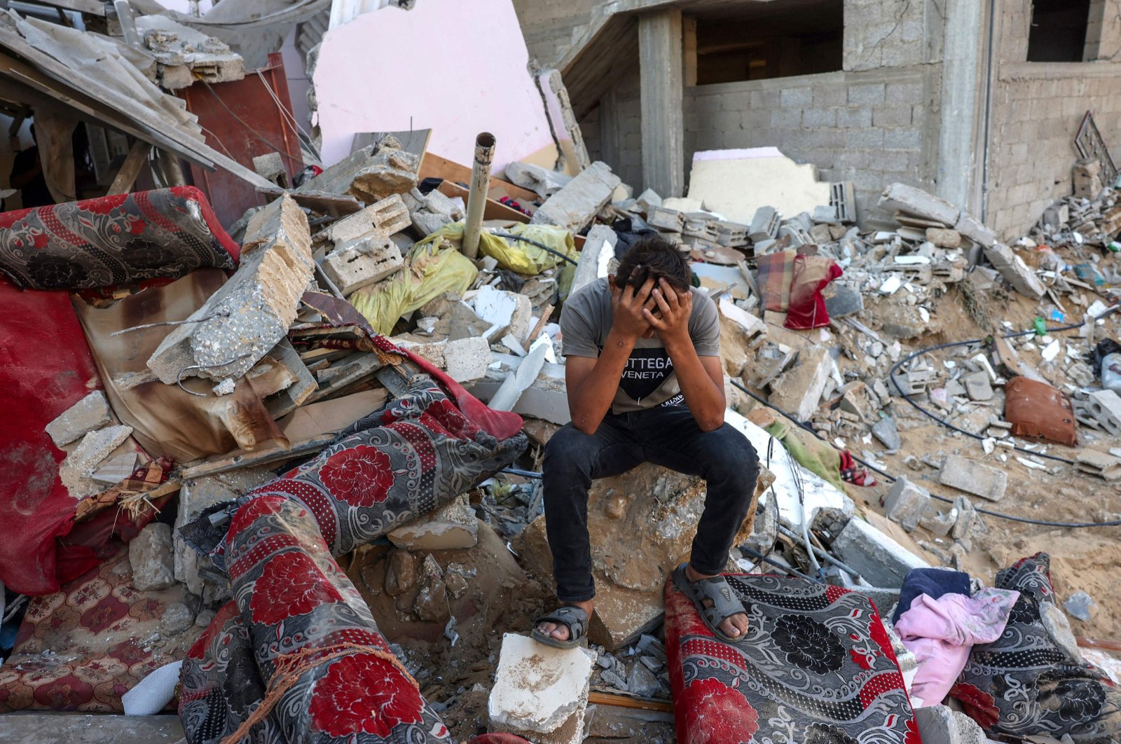 A Palestinian youth reacts as he sits on the rubble following an Israeli military strike on the Rafah refugee camp, in the southern Gaza Strip, Palestine, Oct. 15, 2023. (AFP Photo)