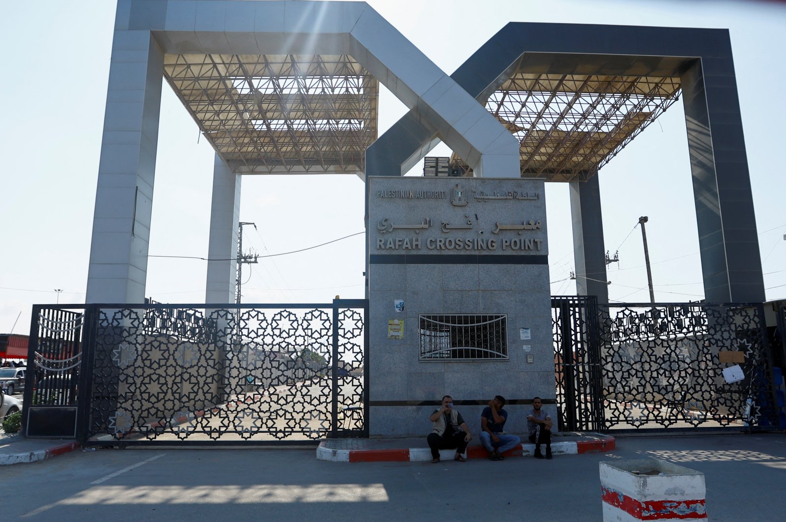 People sit in front of the gates as Palestinians with dual citizenship wait outside Rafah border crossing with Egypt in the hope of getting permission to leave Gaza, Oct. 14, 2023. (Reuters Photo)