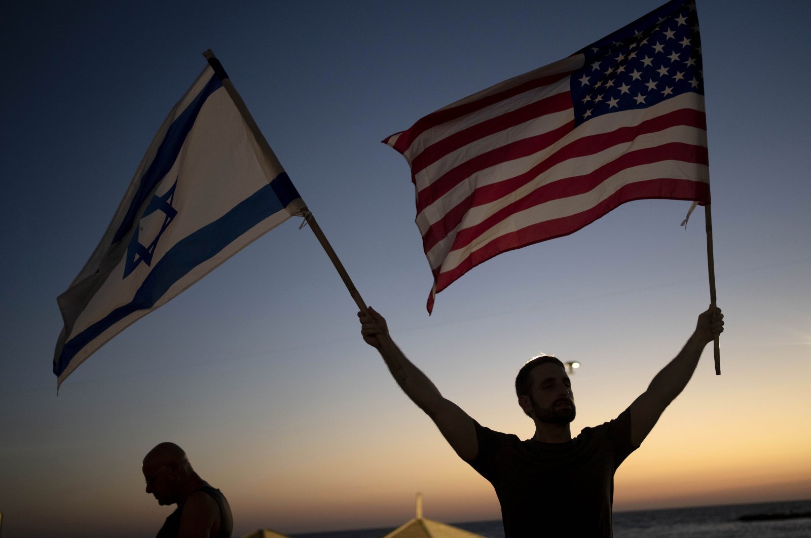 A man waves Israeli and U.S. flags during a protest against plans by Prime Minister Benjamin Netanyahu&#039;s new government to overhaul the judicial system, outside of the U.S. Embassy Branch Office in Tel Aviv, Israel, July 13, 2023. (AP Photo)