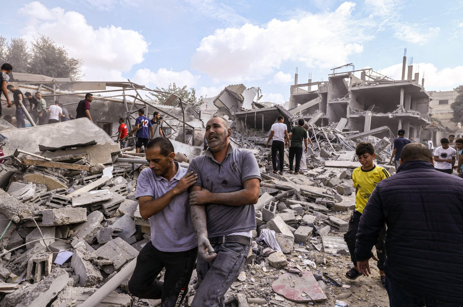 A Palestinian man reacts as he is helped across the rubble following an Israeli airstrike on buildings in Rafah, in the southern Gaza Strip, Palestine, Oct. 17, 2023. (AFP Photo)