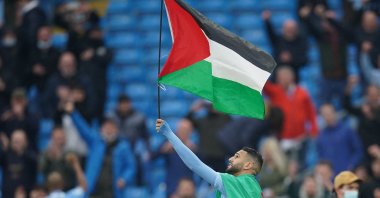 Former Manchester City forward Riyad Mahrez wears the flag of Algeria, as he carries the flag of Palestine at Etihad Stadium, Manchester, U.K., May 23, 2021. (Getty Images Photo)