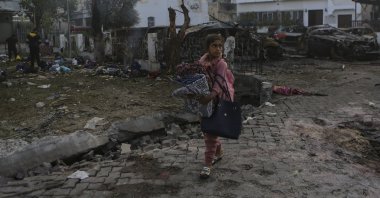 A Palestinian girl carries a blanket as she walks past the site of a deadly airstrike at al-Ahli Baptist Hospital, in Gaza City, Palestine, Oct. 18, 2023. (AP Photo)