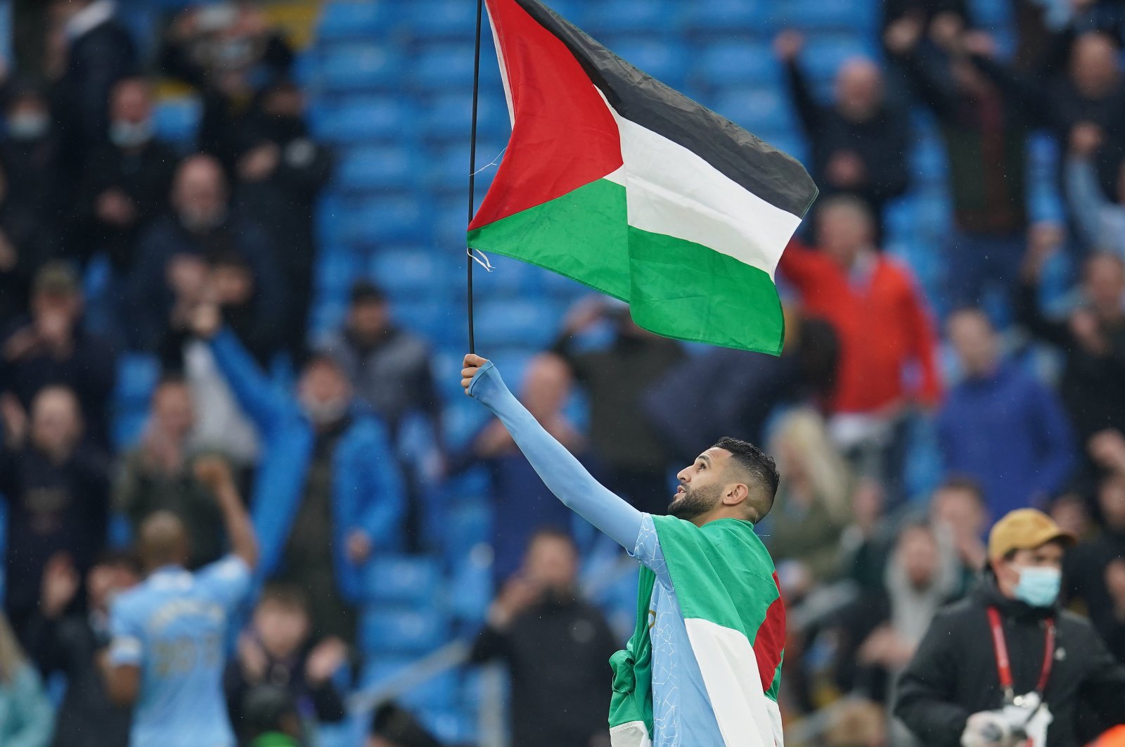 Former Manchester City forward Riyad Mahrez wears the flag of Algeria, as he carries the flag of Palestine at Etihad Stadium, Manchester, U.K., May 23, 2021. (Getty Images Photo)