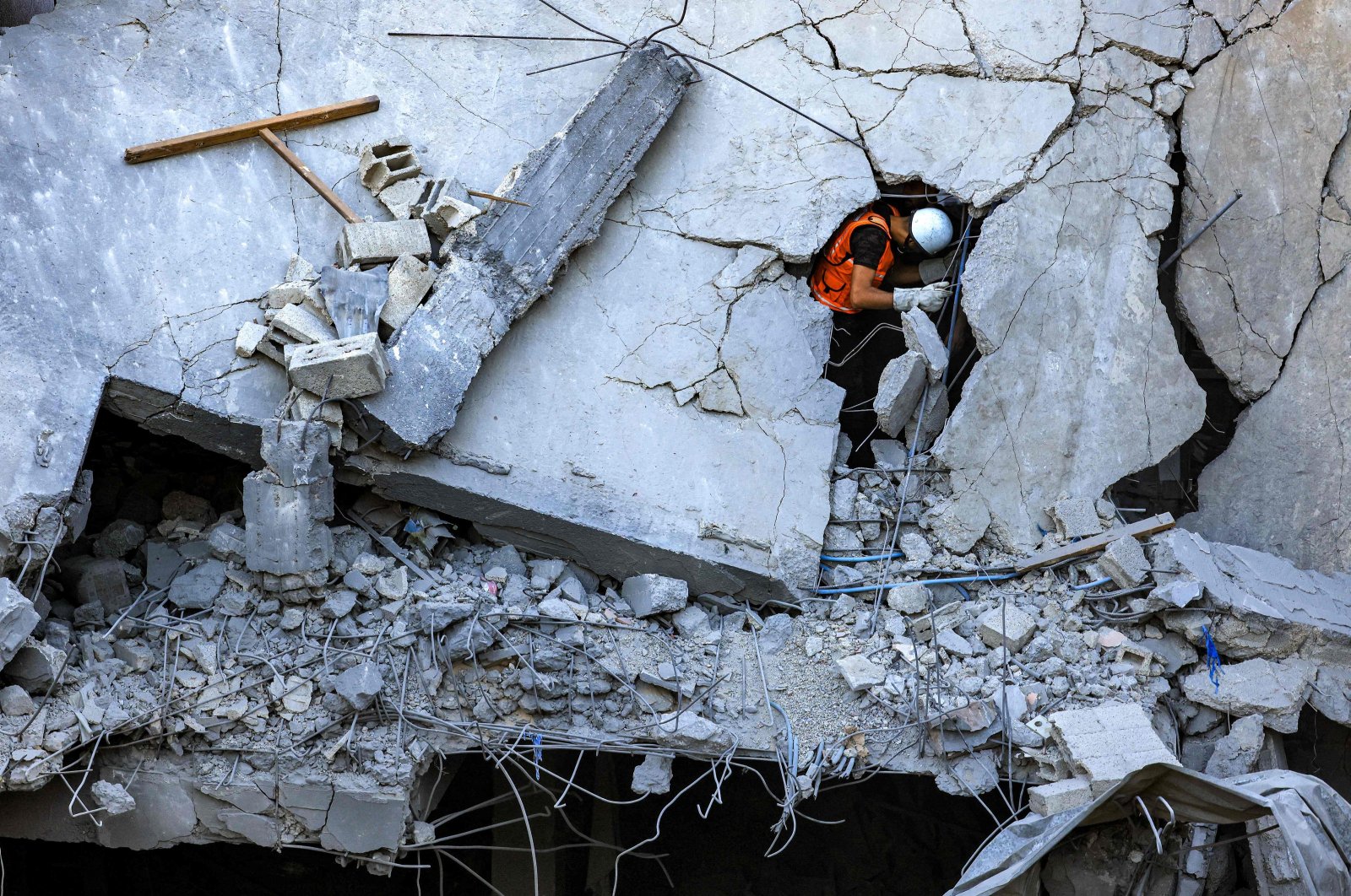 A Palestinian civil defense member stands through a crack in a collapsed building hit by Israeli bombardment in Khan Yunis, southern Gaza Strip, Palestine, Oct. 19, 2023.