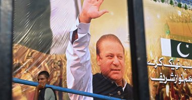 A laborer walks past a large banner of Pakistan&#039;s former PM Nawaz Sharif displayed at a park in Lahore, Pakistan, Oct. 19, 2023. (AFP Photo)