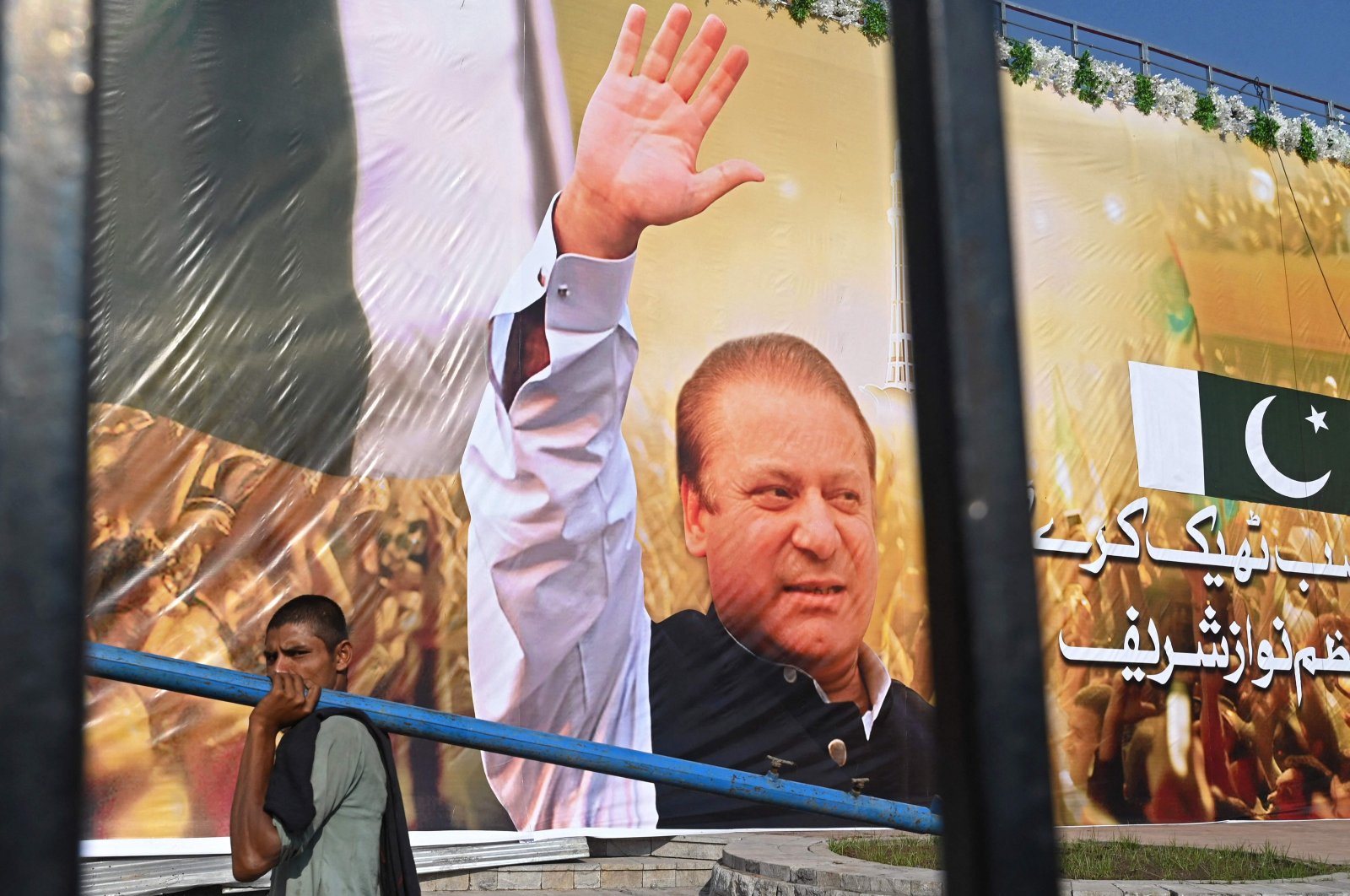 A laborer walks past a large banner of Pakistan&#039;s former PM Nawaz Sharif displayed at a park in Lahore, Pakistan, Oct. 19, 2023. (AFP Photo)