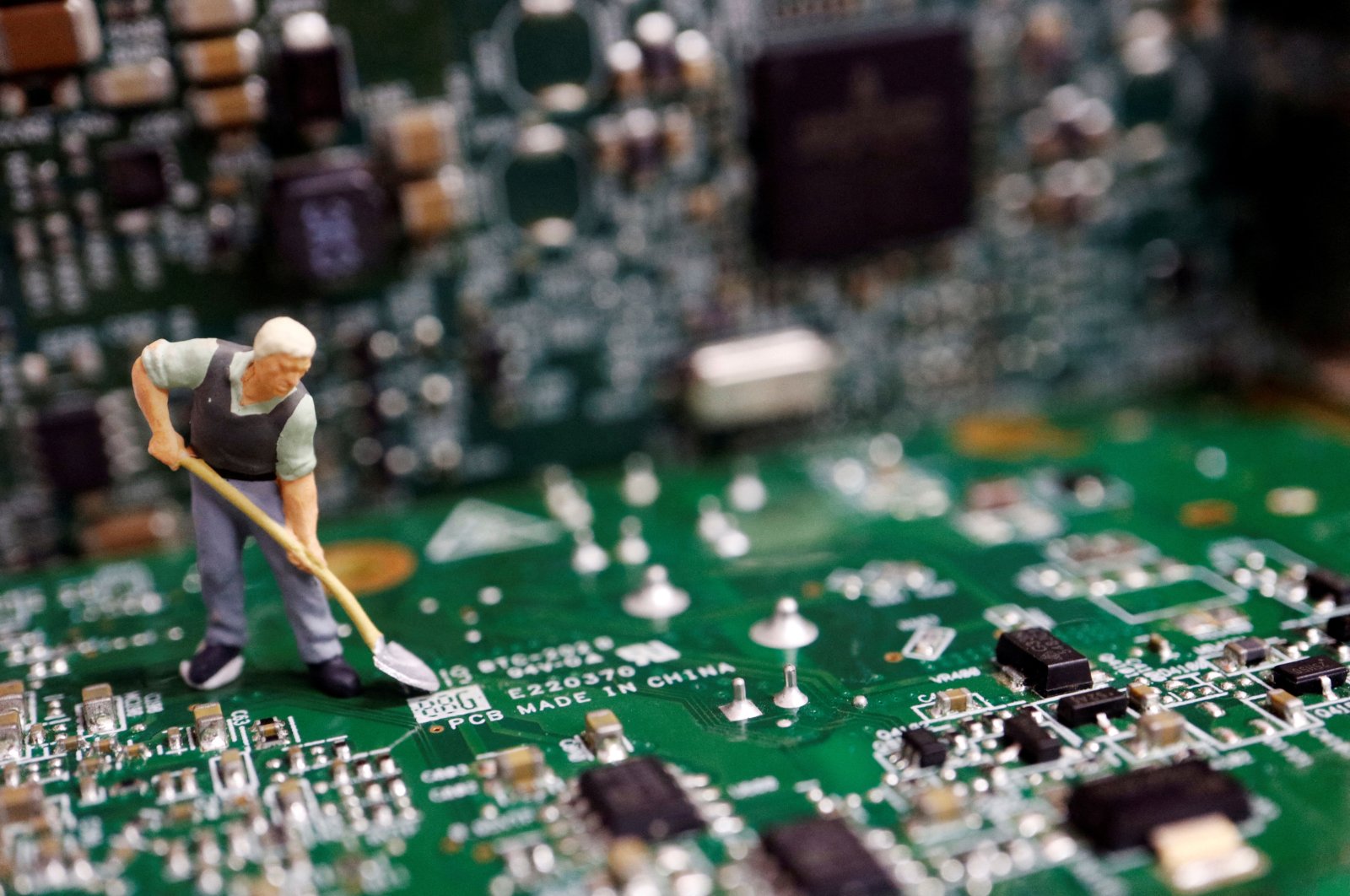 A worker miniature is placed among printed circuit boards with semiconductor chips, in this illustration taken on July 5, 2023. (Reuters Photo)