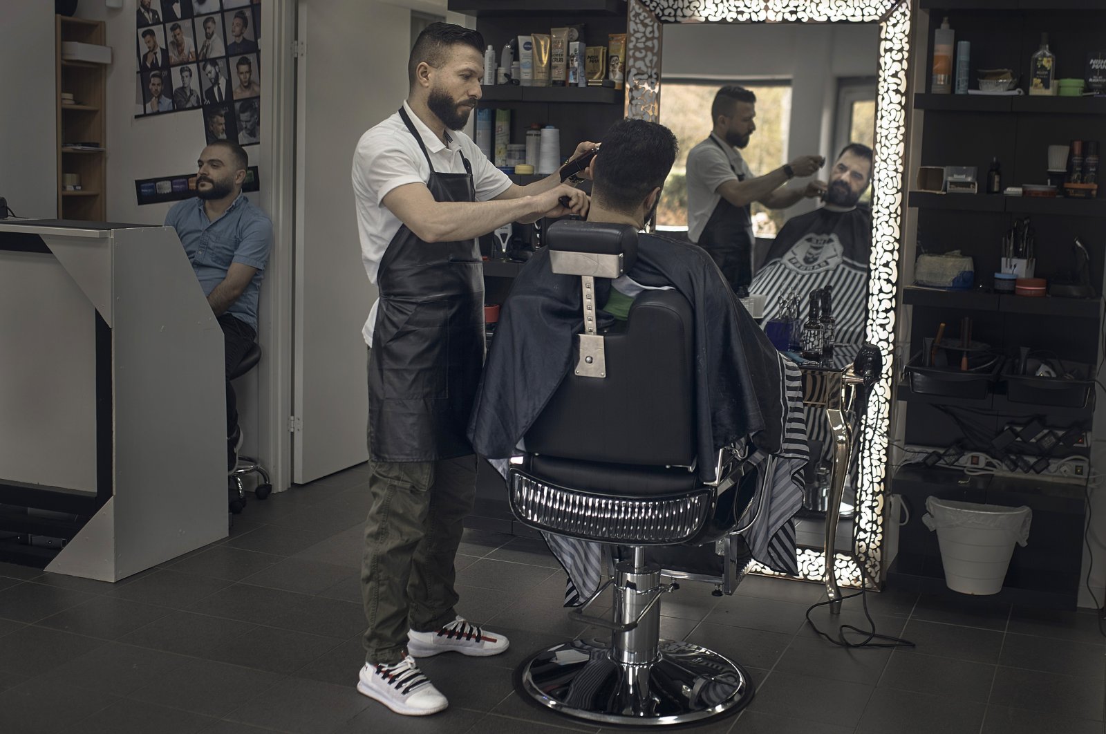 Hairdresser Hasan Derek, 36, from Syria, cuts the hair of a customer in Akalla, Rinkeby-Kista borough, Stockholm, Sweden, April 28, 2020. (AP Photo)