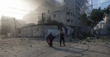 A Palestinian man helps a woman flee a destroyed area following an Israeli airstrike in Gaza, Palestine, Oct. 21, 2023. (EPA Photo)