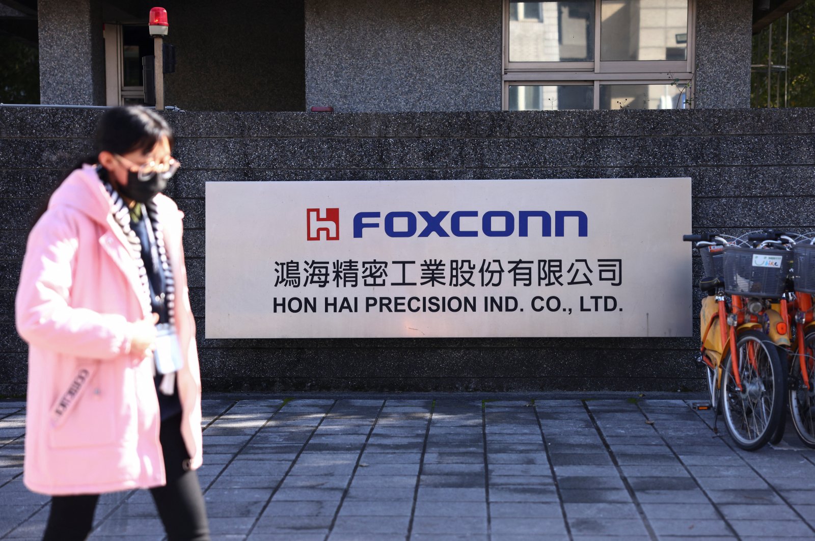 A woman walks past the logo of Foxconn outside a company&#039;s building, in New Taipei City, Taiwan Dec. 22, 2022. (Reuters Photo)
