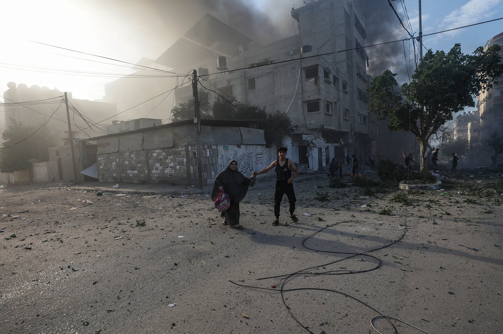 A Palestinian man helps a woman flee a destroyed area following an Israeli airstrike in Gaza, Palestine, Oct. 21, 2023. (EPA Photo)