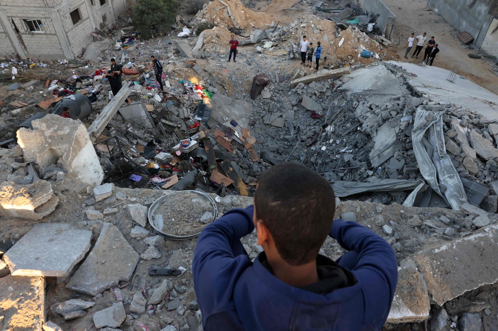 A young boy looks on as people check the rubble of a building destroyed in an Israeli bombardment in Rafah in the southern Gaza Strip, Palestine, Oct. 21, 2023. (AFP Photo)