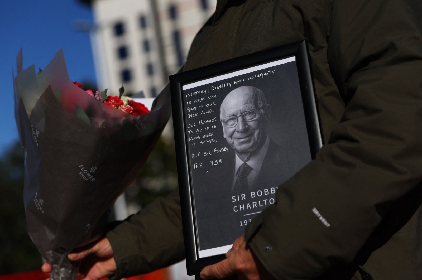 A fan is seen with a framed Bobby Charlton picture and flowers outside Old Trafford, Manchester, U.K., Oct. 22, 2023. (Reuters Photo)