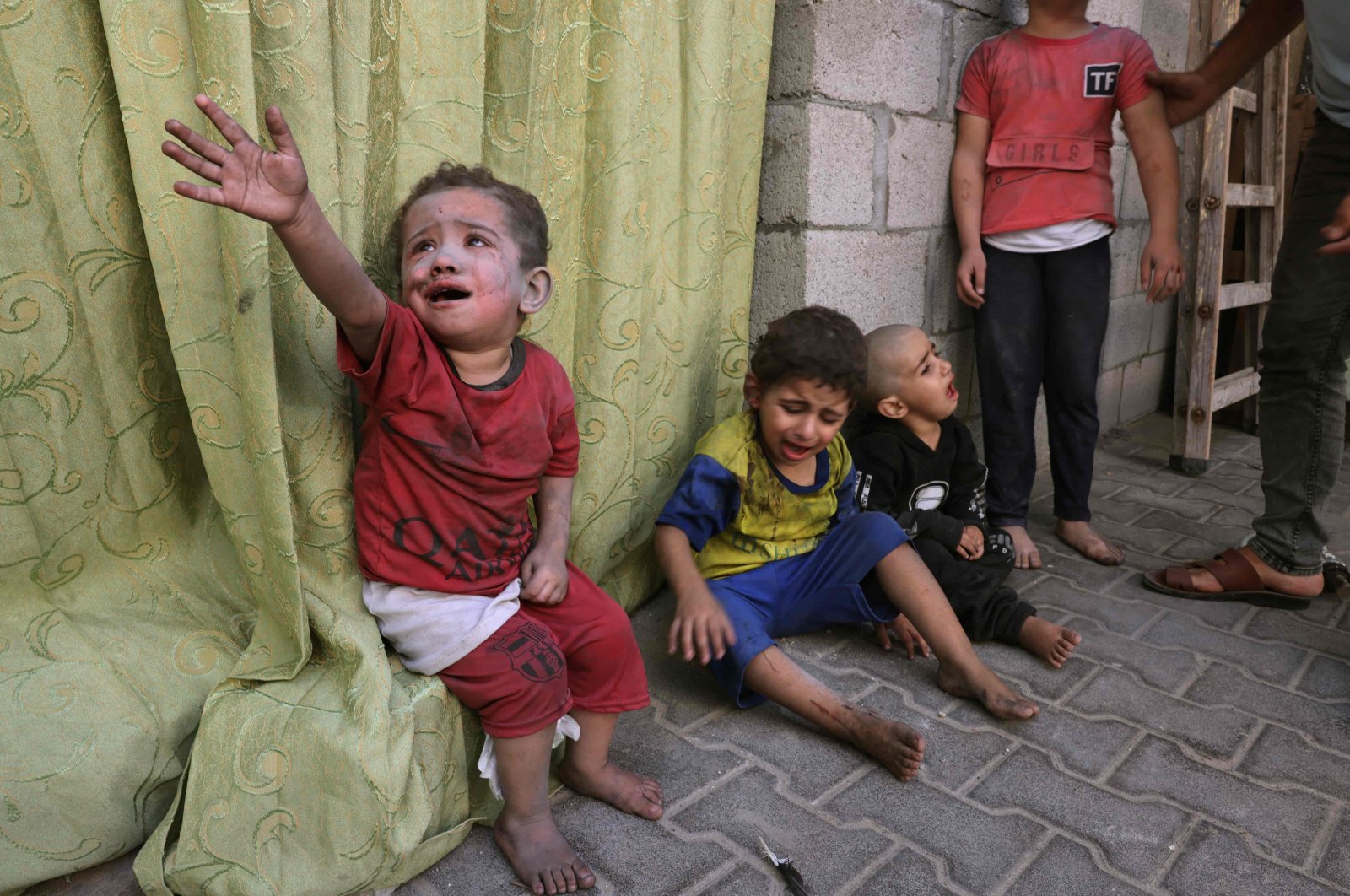 Palestinian children covered in dust from an Israeli air strike sit on the grounds of a hospital in Rafah, in the southern Gaza Strip on Oct. 23, 2023. (AFP Photo)