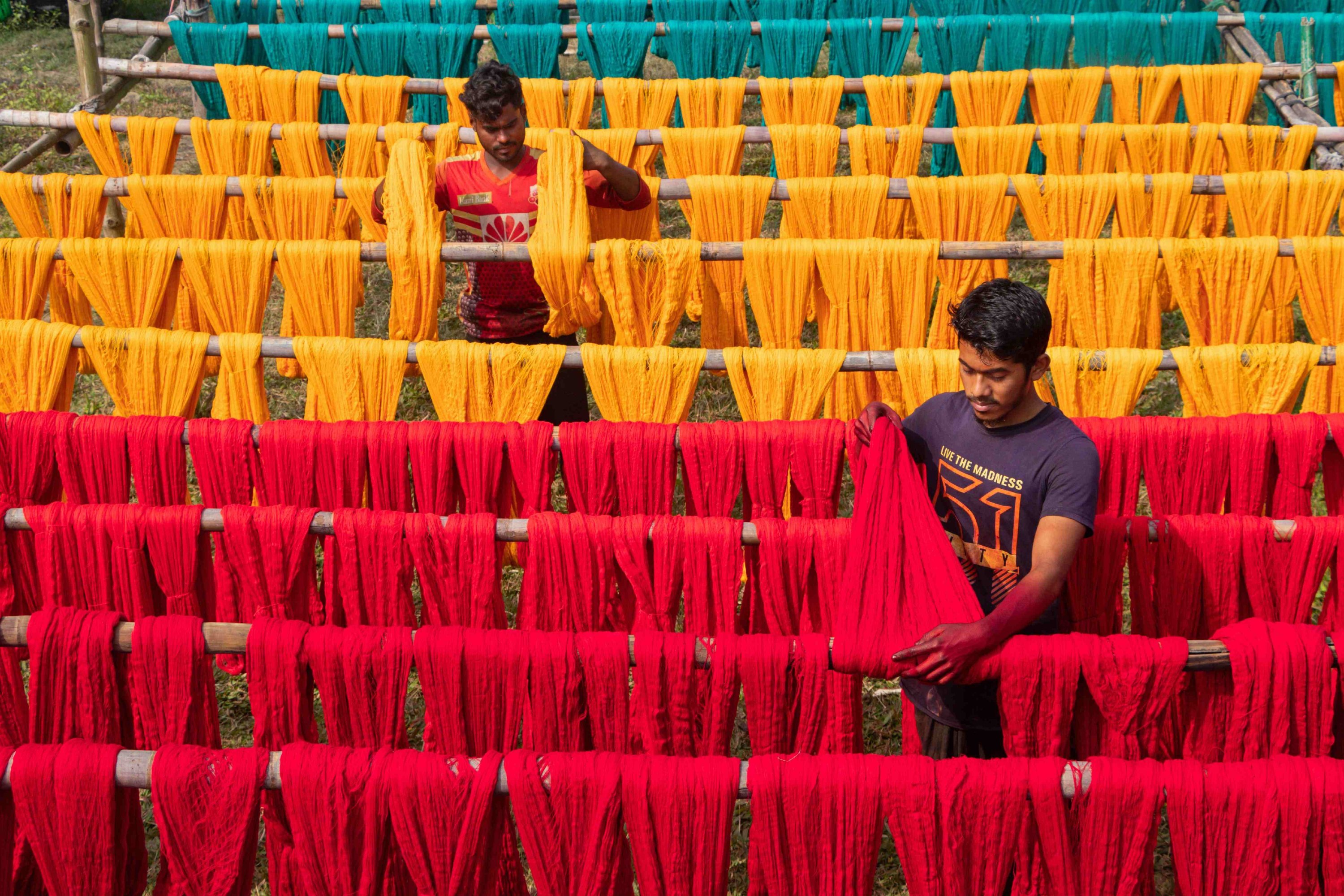 Workers hang freshly dyed threads on a wooden structure as they are being dried in the sunshine in Narayanganj, Bangladesh. (Getty Images Photo)