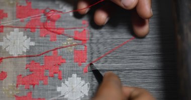 A Handloom weaver weaves a Jamdani saree on a traditional wooden hand-weaving loom at Demra Jamdani Palli, Dhaka, Bangladesh, Sept. 19, 2022. (Getty Images Photo)