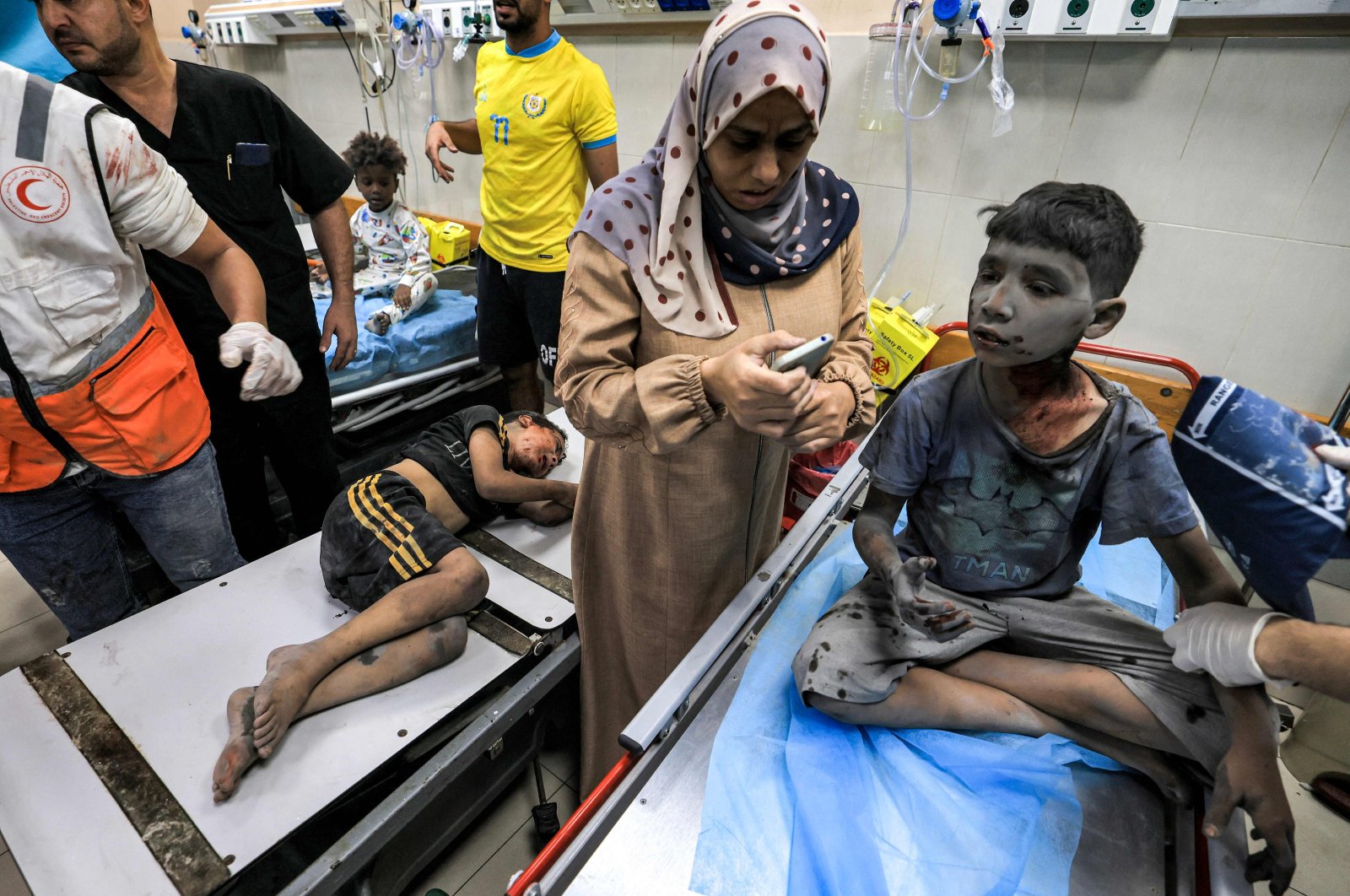 A woman uses a phone while waiting with two children injured in Israeli bombardment about to receive emergency treatment at a trauma ward at Nasser hospital in Khan Yunis in the southern Gaza Strip on Oct. 24, 2023. (AFP Photo)